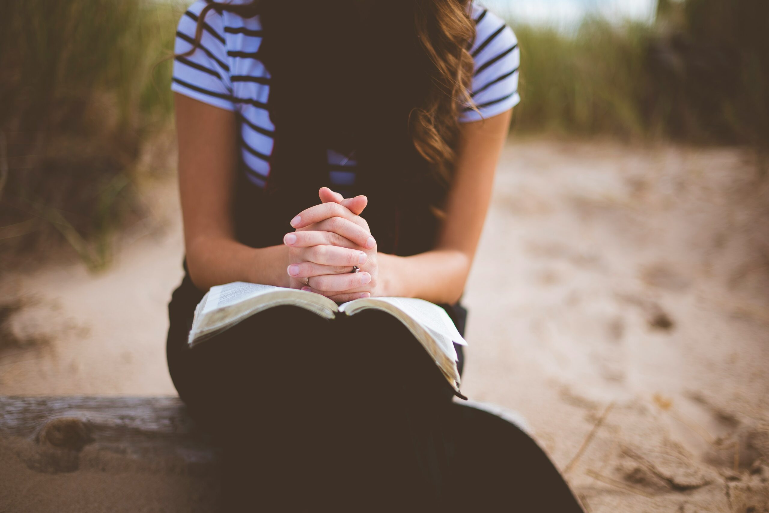 woman sitting and praying with Bible