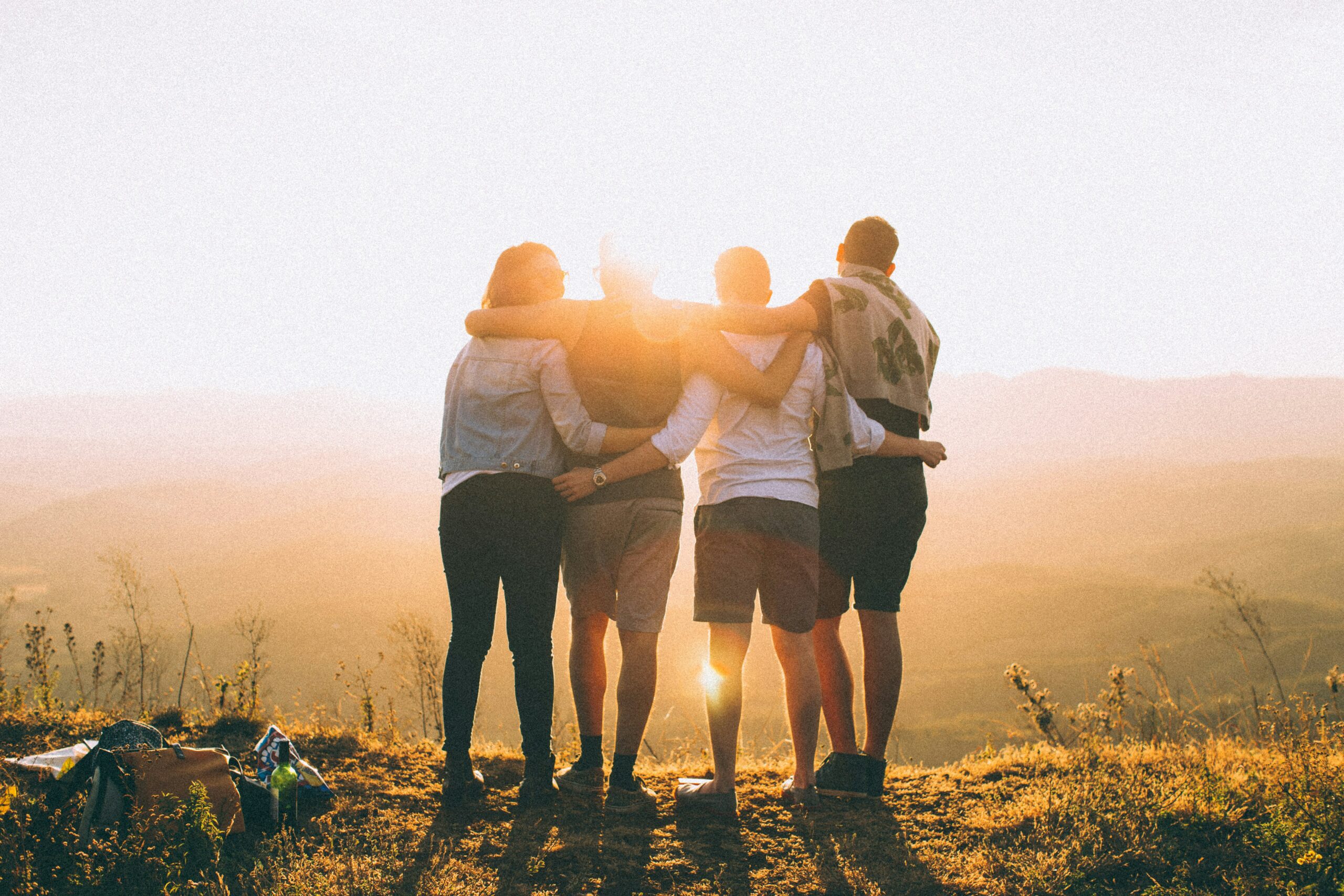 friends standing on a hill gazing at the sunset