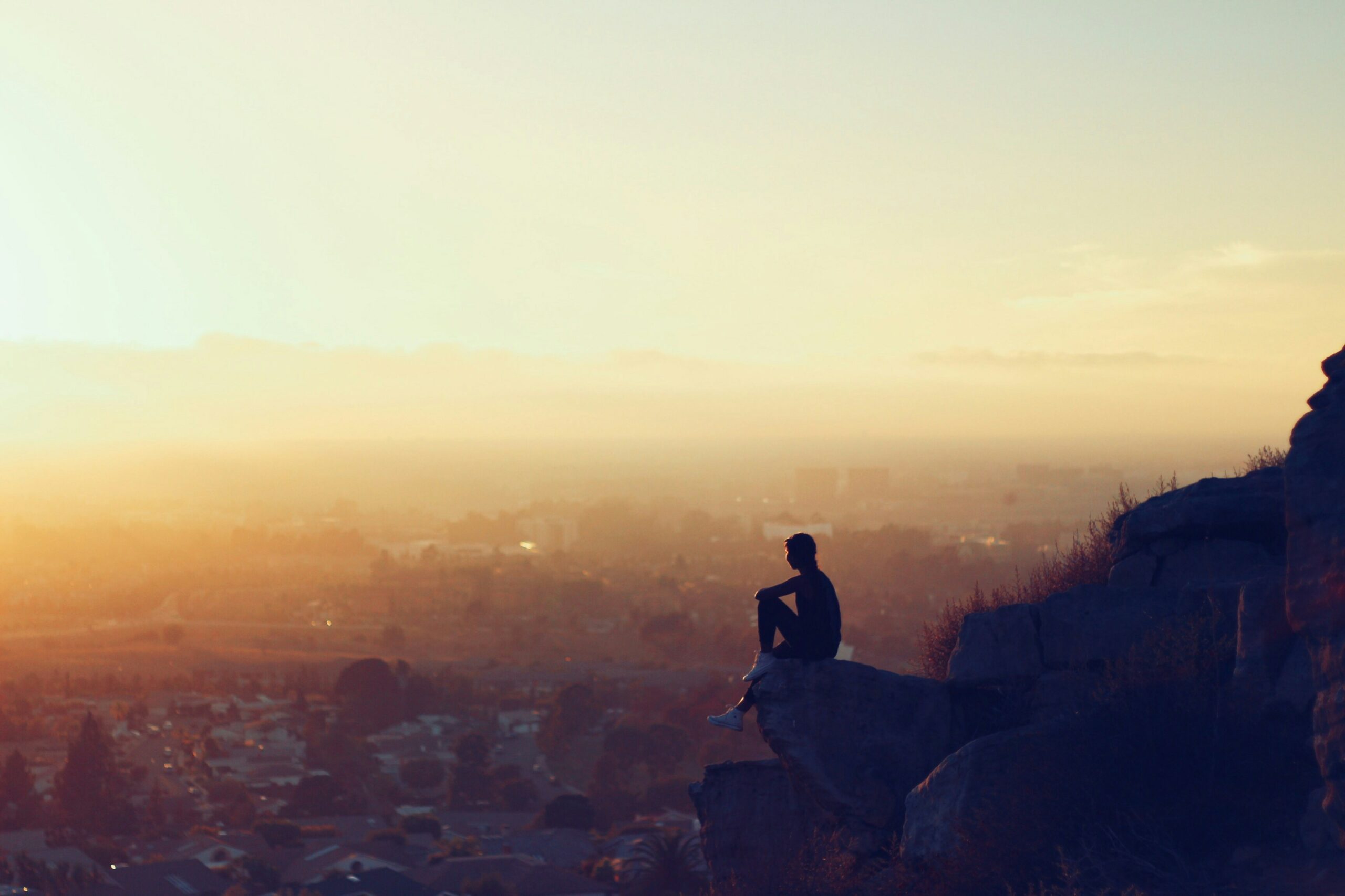 man sitting on mountain in front of sunrise